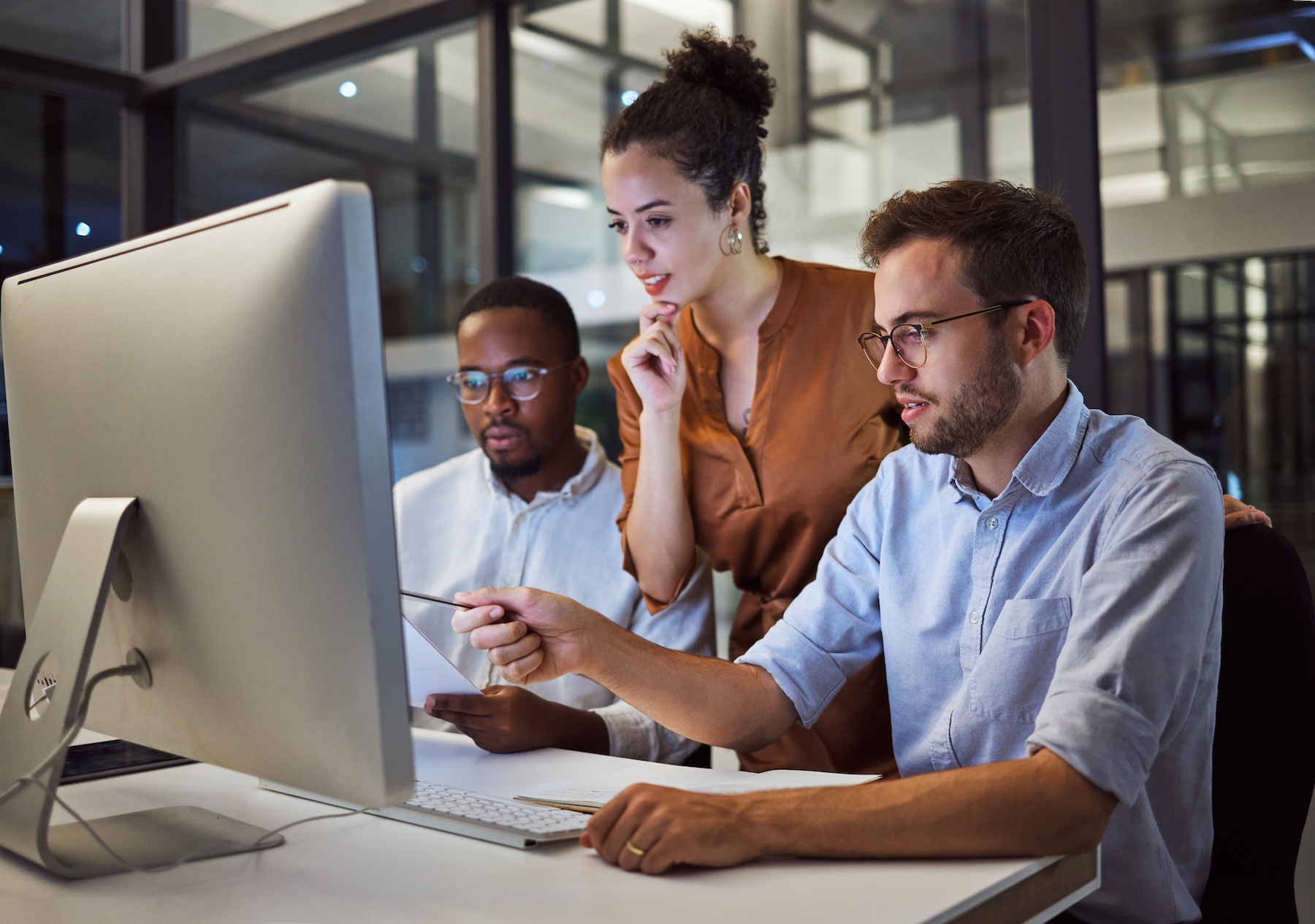 Man using devices for online business order at bakehouse Team of three workers sitting in front of one office computer, collaborating on an issue