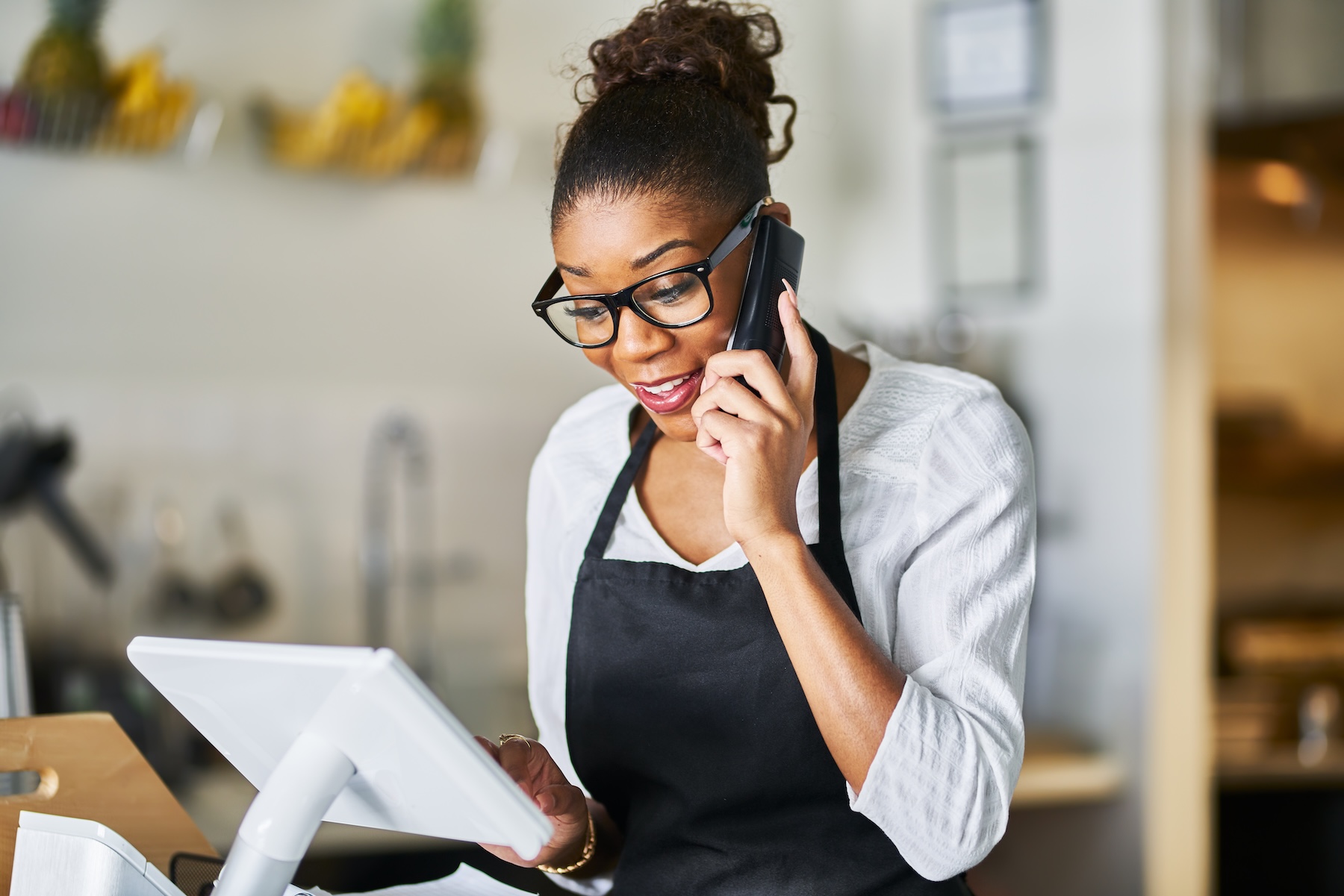 Waitress in small restaurant taking order over phone onto POS terminal