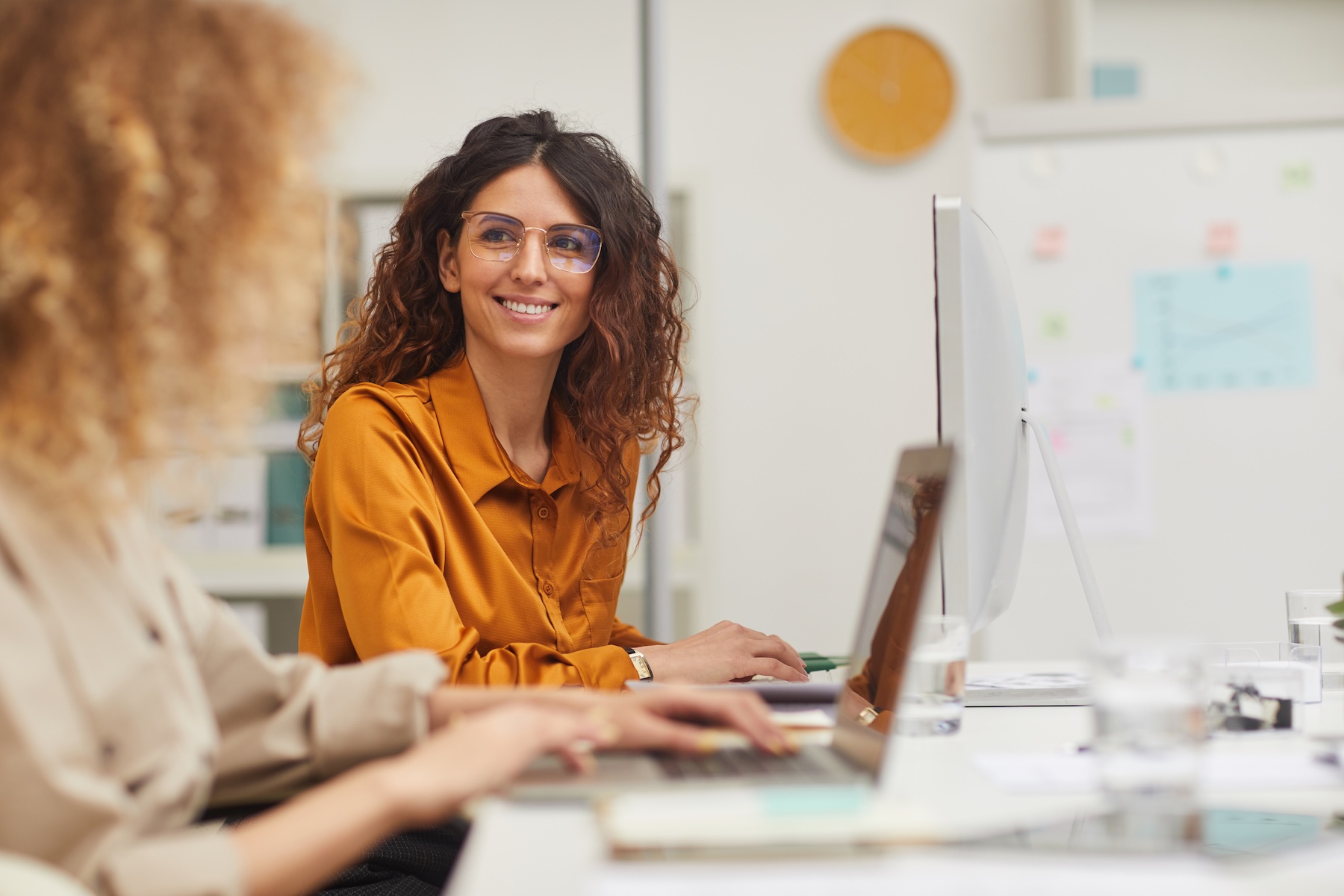 Two female employees work together in small office