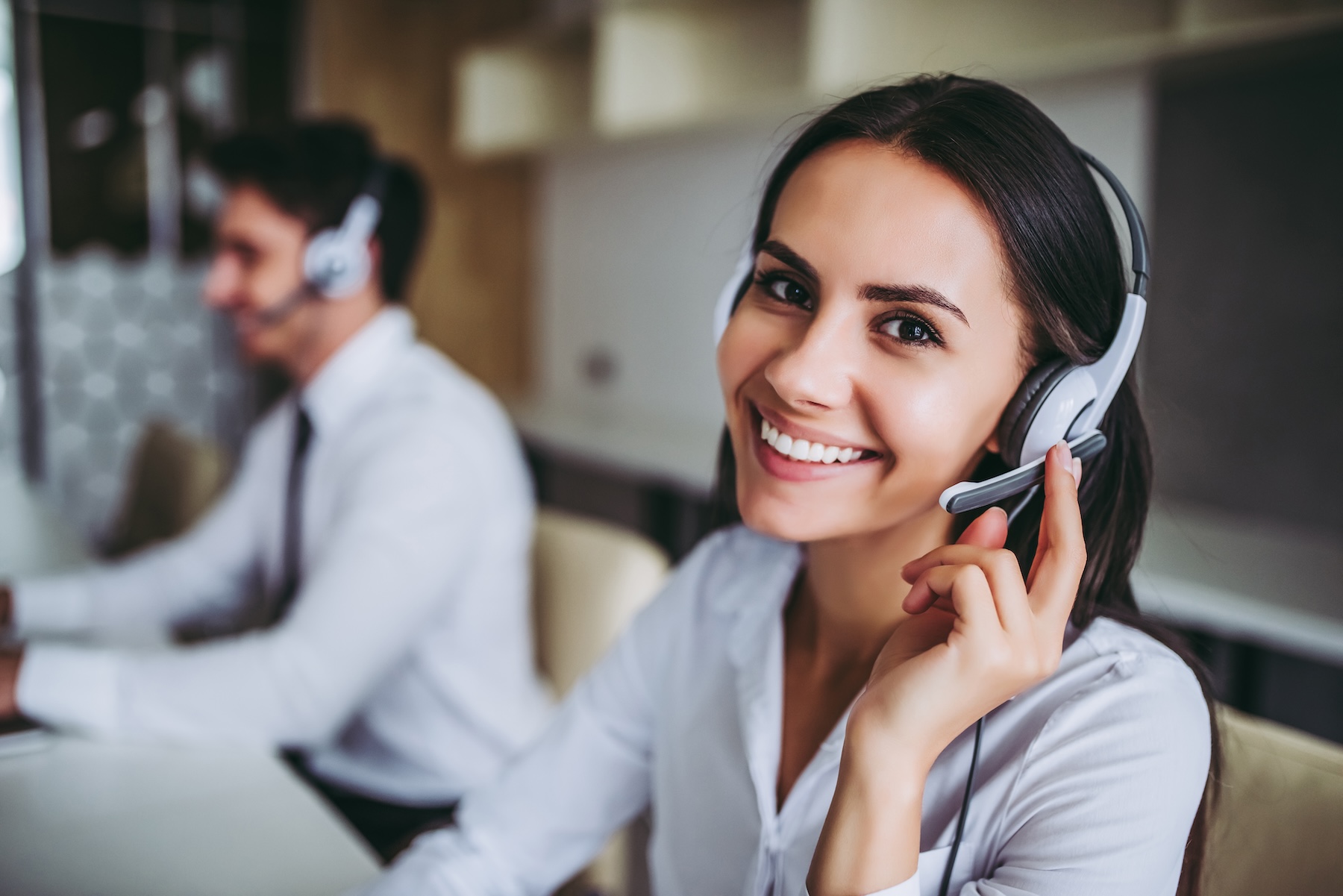 Smiling call center workers in headphones working at modern office.