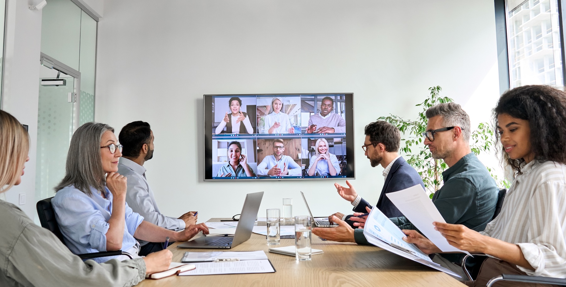 Diverse company employees having online business conference video call on TV
